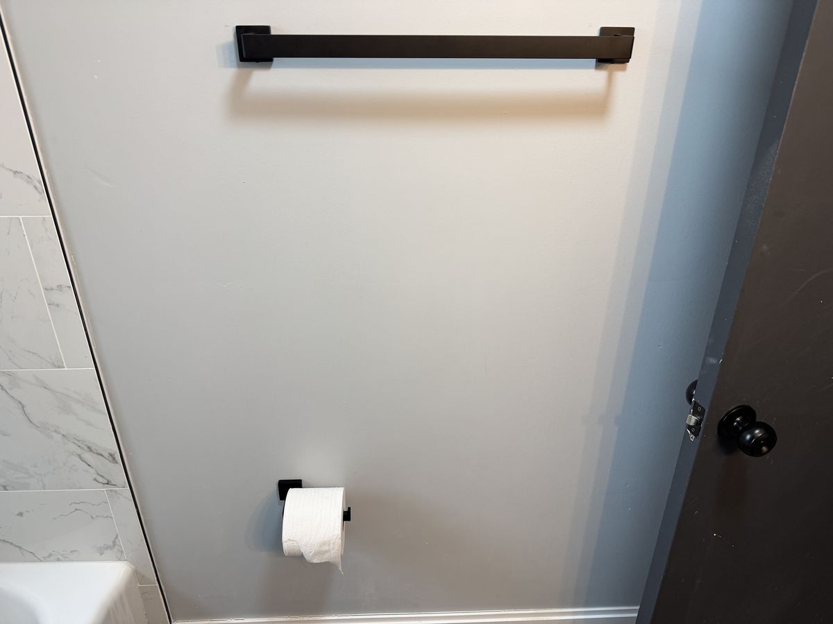 Black matte bathroom hardware mounted on marble tile