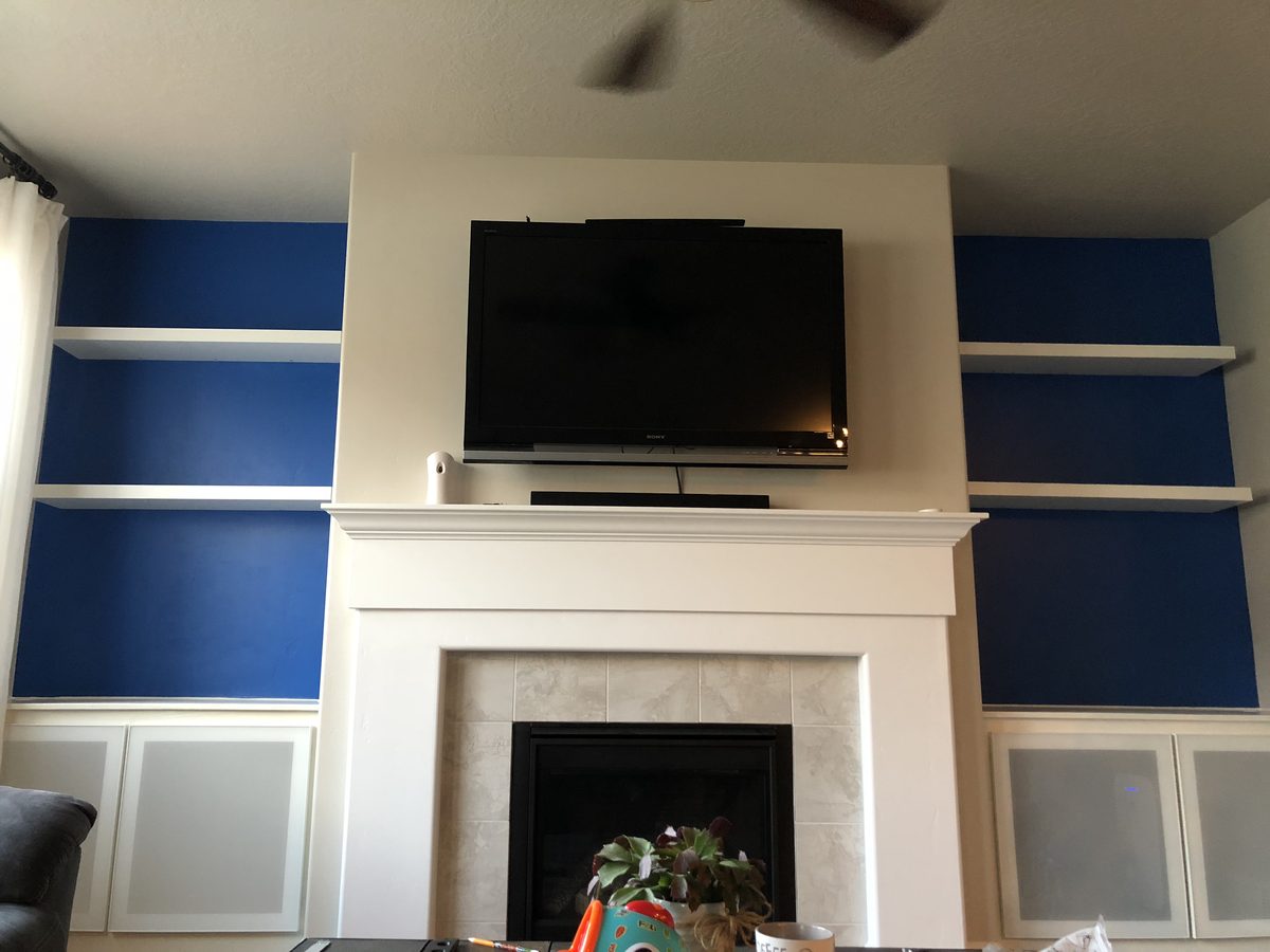 Completed built-in shelving with TV mounted above fireplace